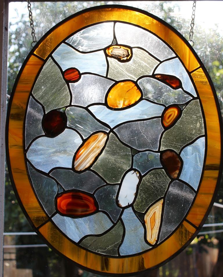Brown and white geodes in an oval stained glass panel 